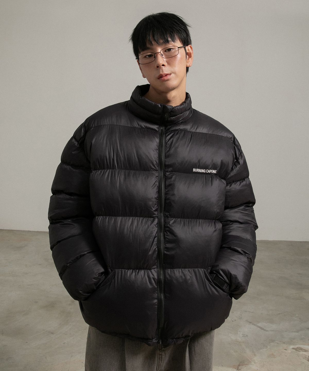 블랙 컬러의 버닝카포네 패딩이 침대 위에 깔끔하게 놓여 있는 모습과 택이 붙어 있는 근접샷