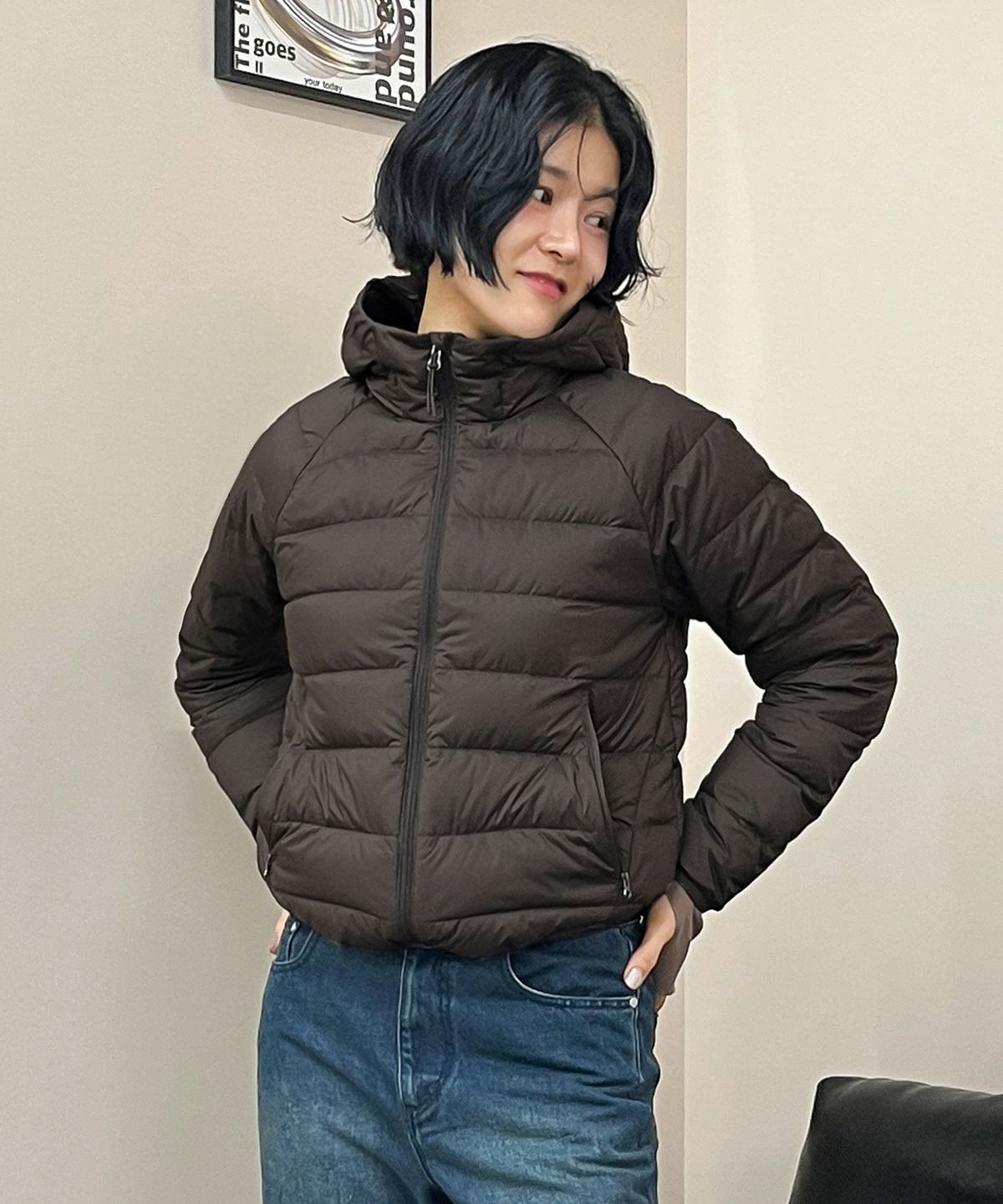 162cm의 사촌 동생이 브라운 패딩을 입고 카페 의자에 앉아 있는 자연스러운 착용 샷